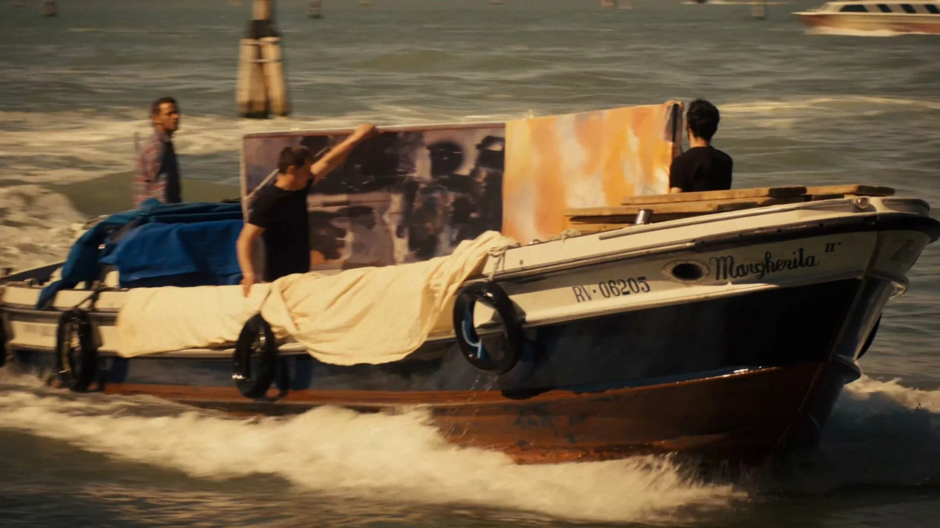 3 men in a boat transporting a large painting