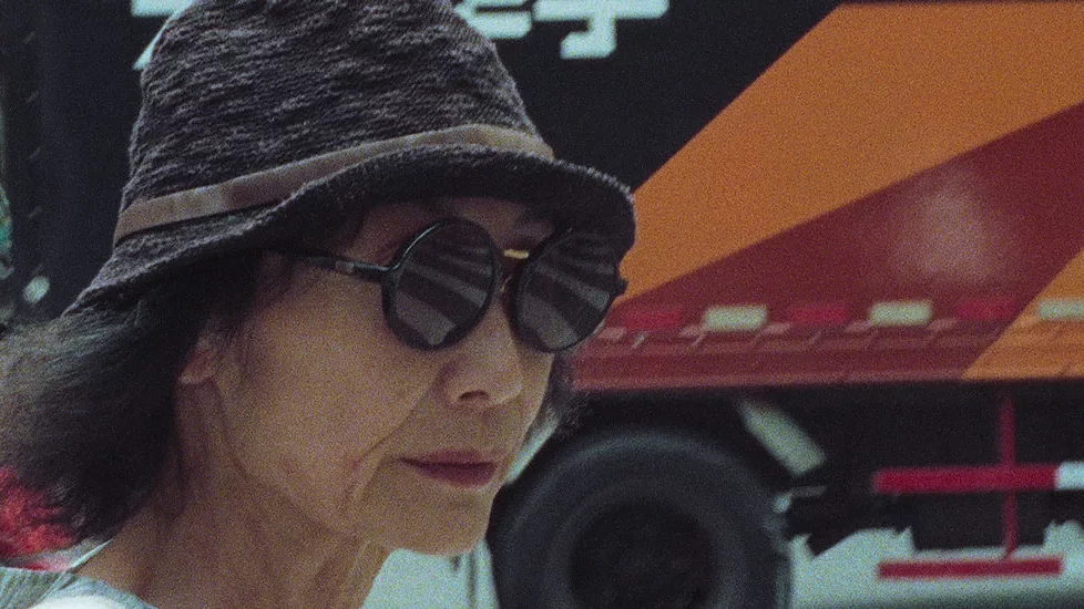A woman in sunglasses and a hat also wears an expression of determination.