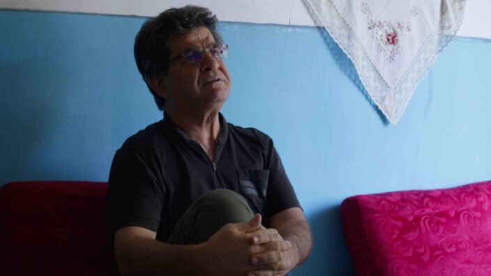 A man in glass looks up and to his left. That man is Jafar Panahi!