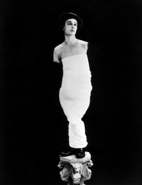 Buster Keaton impersonating Venus de Milo in a white toga