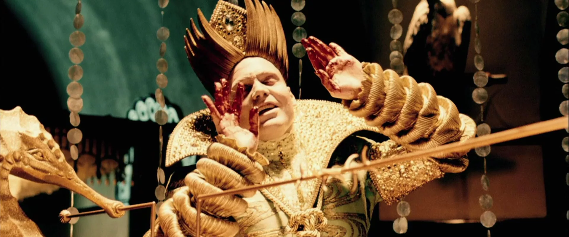 A man in golden overalls of a king going crazy and fumbling the air with his blood-covered hands