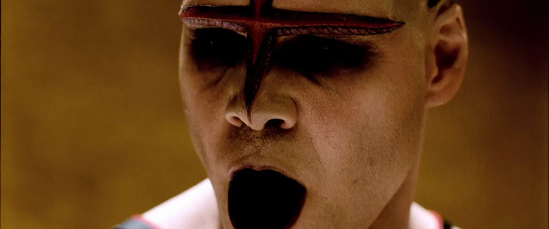 A Japanese man with a cross on his forehead and a black gaping hole instead of a mouth