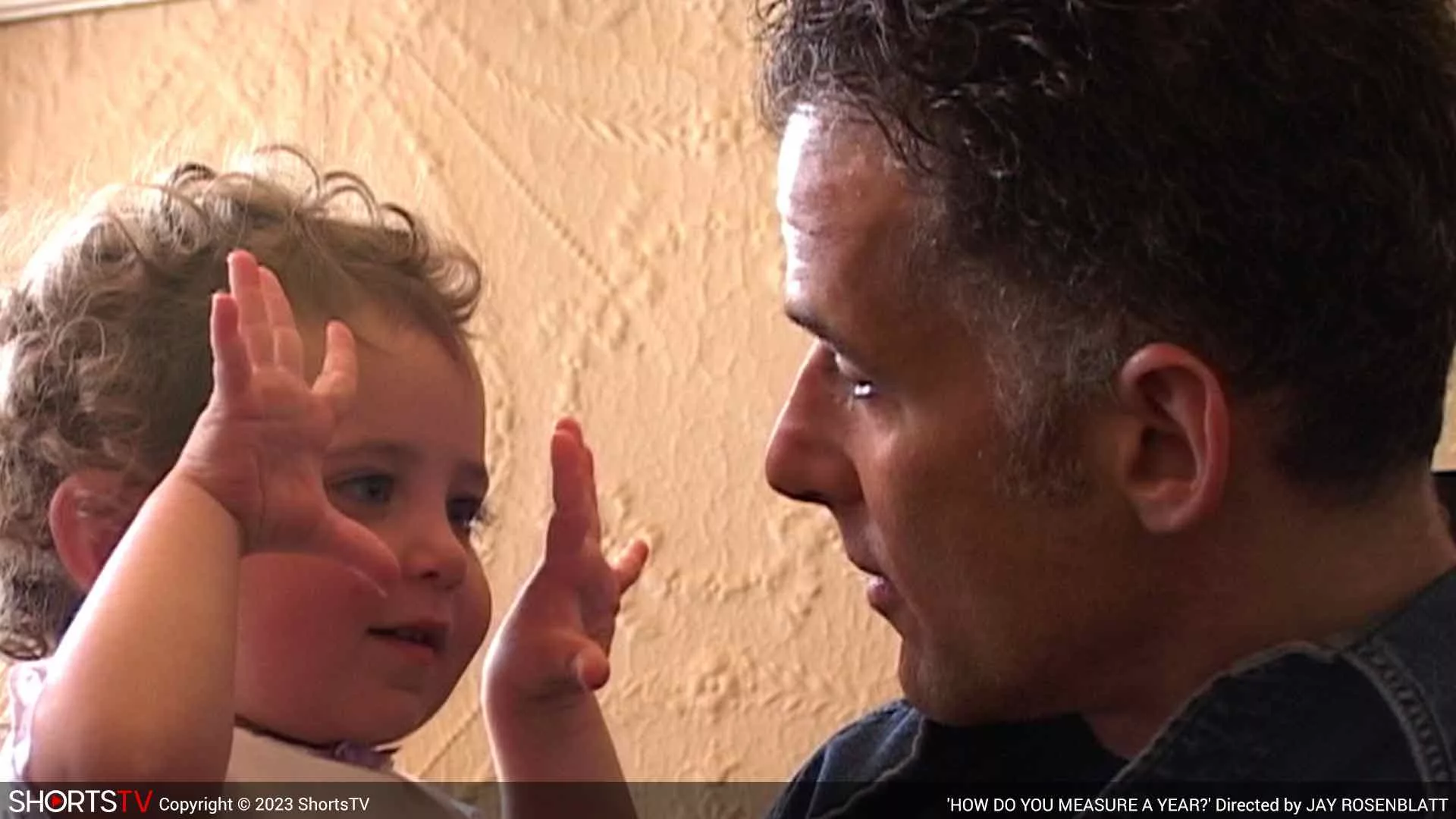 A father (Jay Rosenblatt) watching his little curly-haired daughter (Ella) as she shows him her palms in How do you measure a year?, an Oscar 2023 nominated short documentary