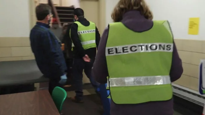 Two men in green working jackets with Election word written on their backs