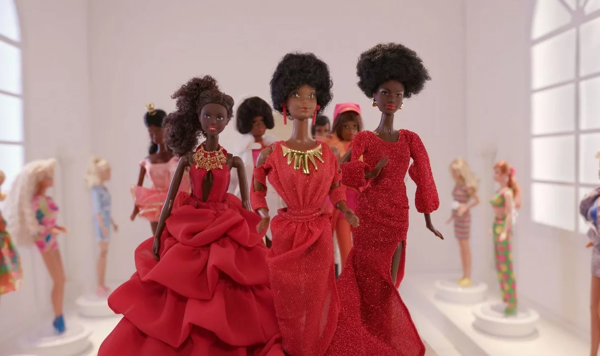 A lot of black barbie dolls standing in a circle in red ball dresses
