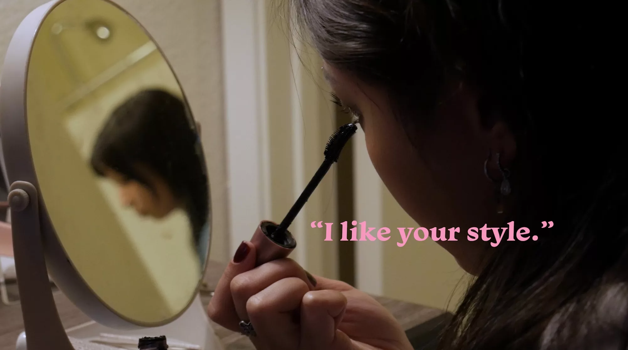 Girl applying mascara as she looks in the mirror