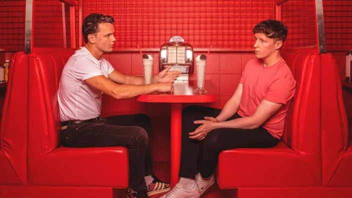Two guys sitting at a table in a red-color diner