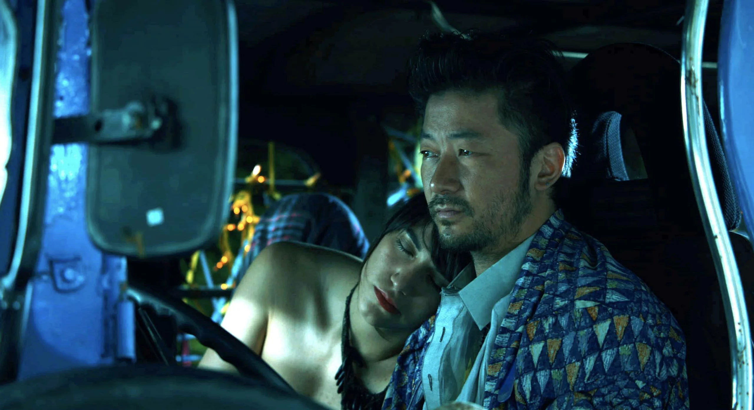 A man and woman sitting in the cab of a truck or bus.