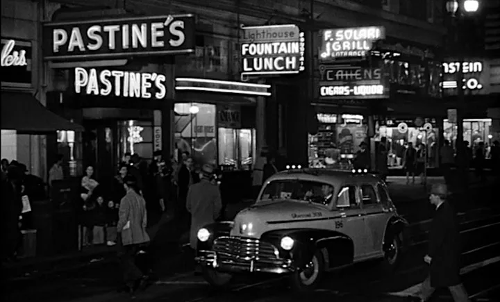 Black and white image with neon signs lighting up the street below.