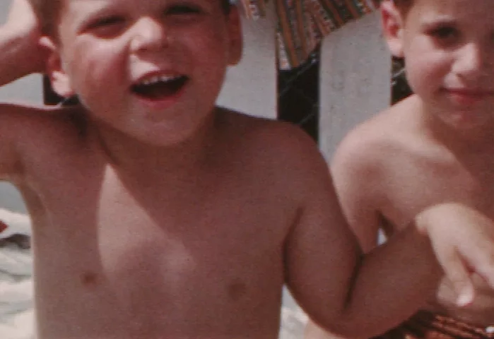 A 4-color image of two young boys, possibly at a beach, one of whom looks at the camera with his mouth open