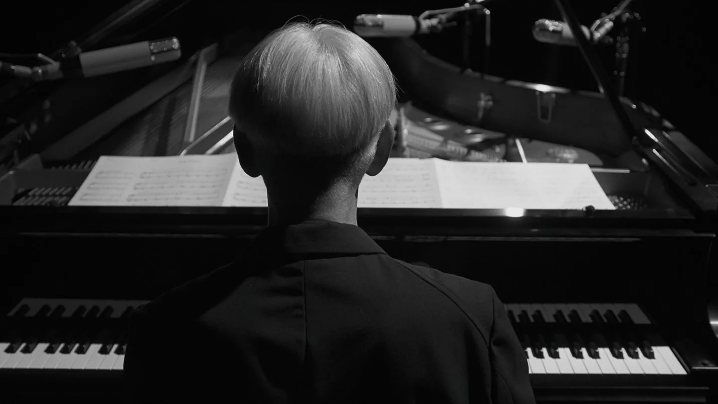 a man sitting facing a piano.