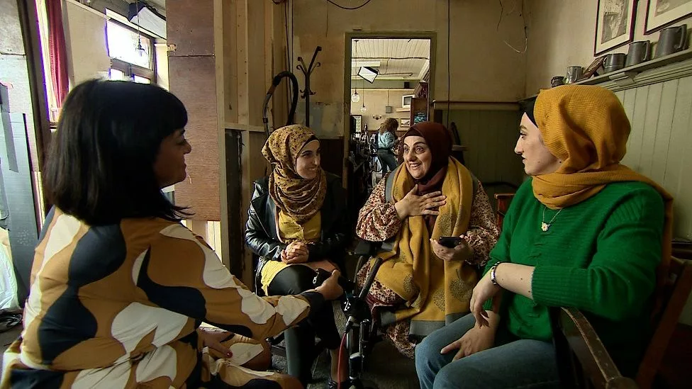 Four women, three of whom are in headscarves, sit in a circle