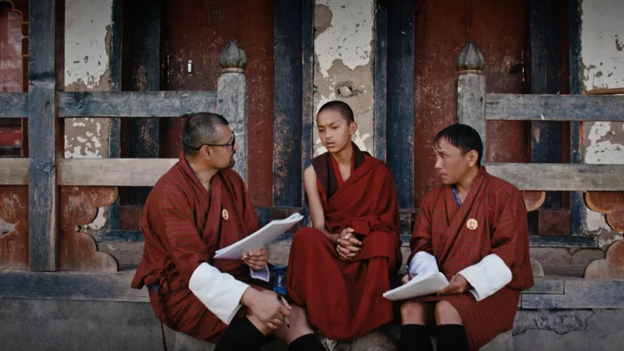 Three men in monk robes sitting
