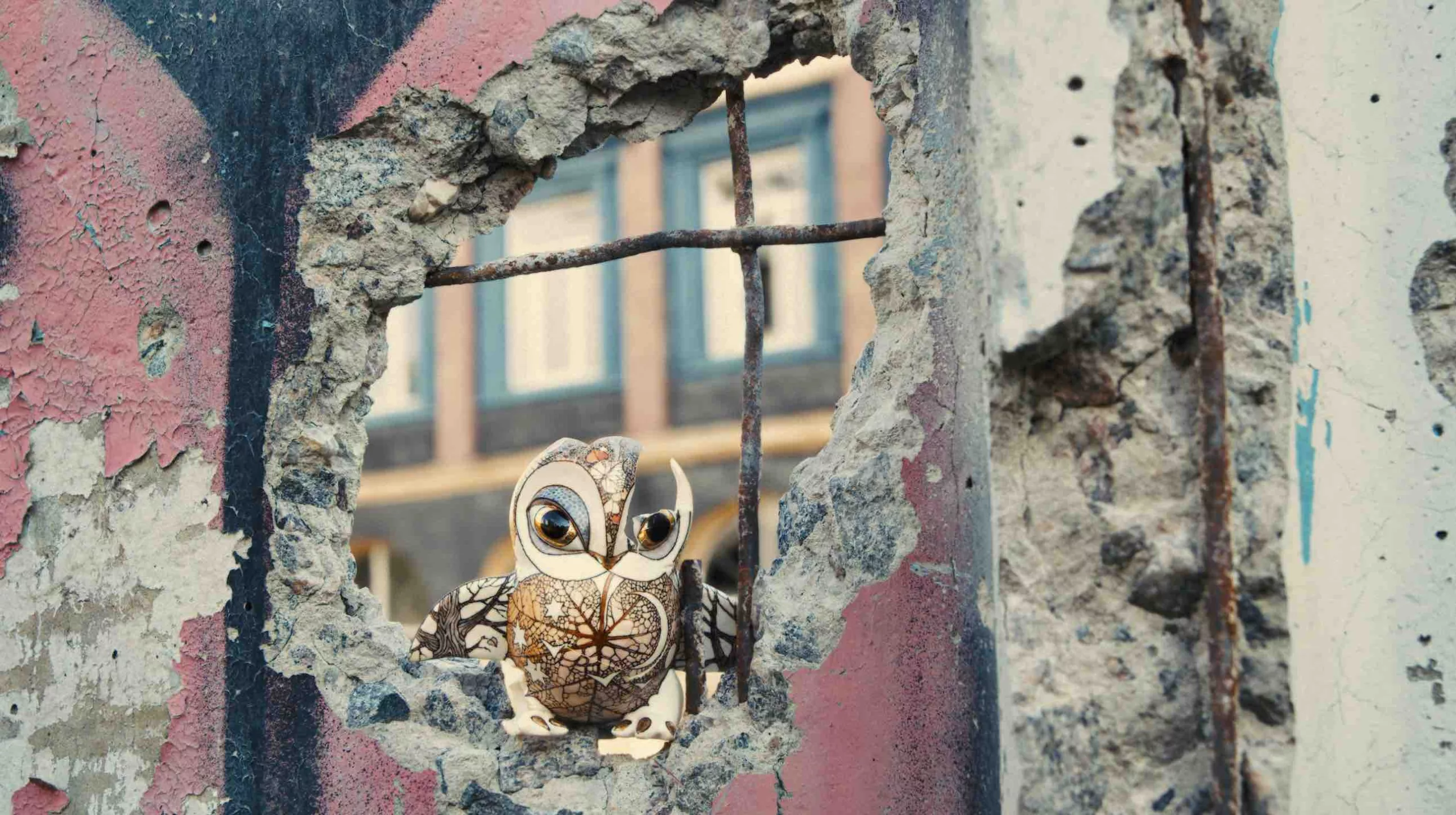 A small, delicate porcelain owl is placed in the hole of a wall created by Russian artillery.