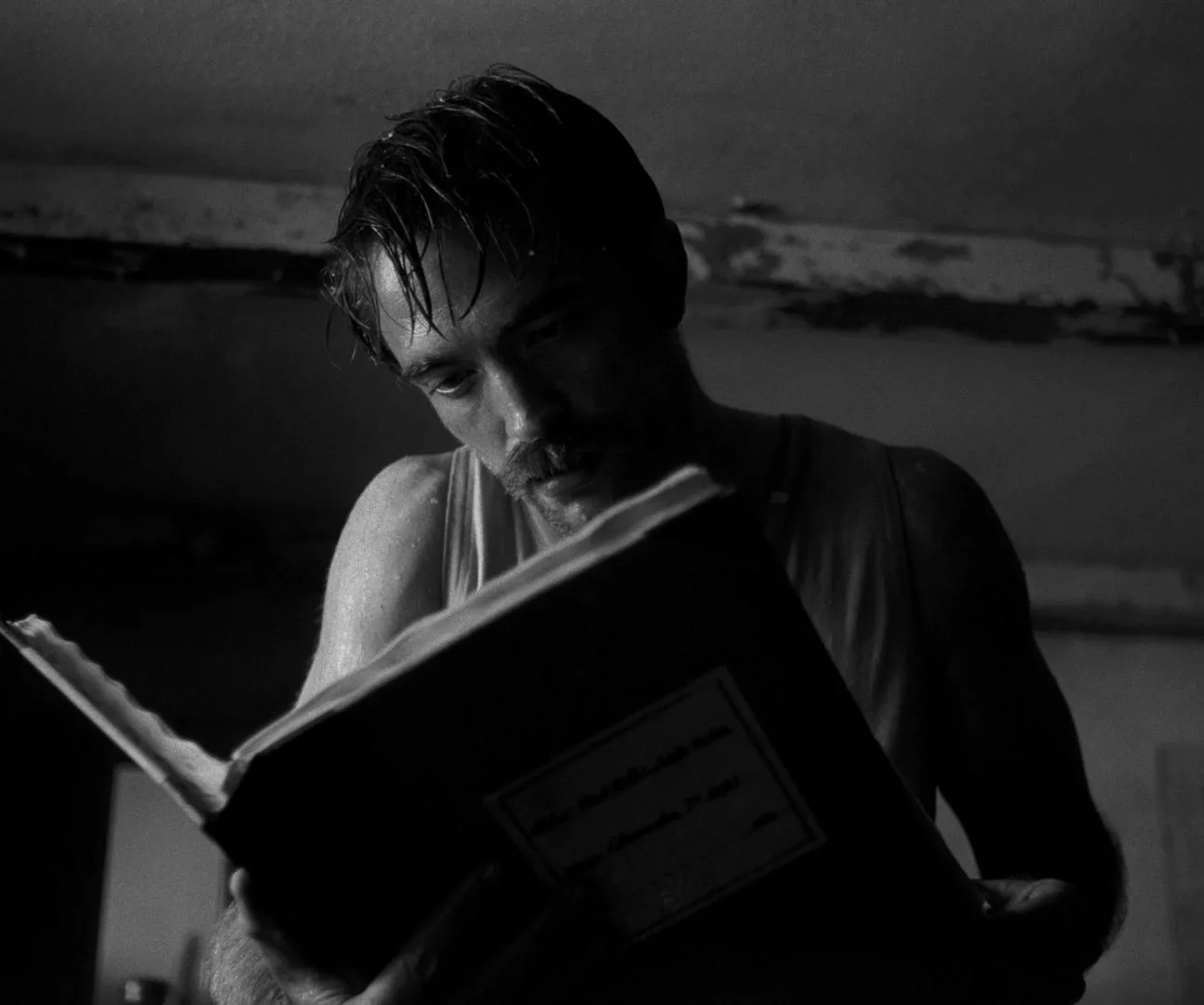 Young, sweaty man reading a large book