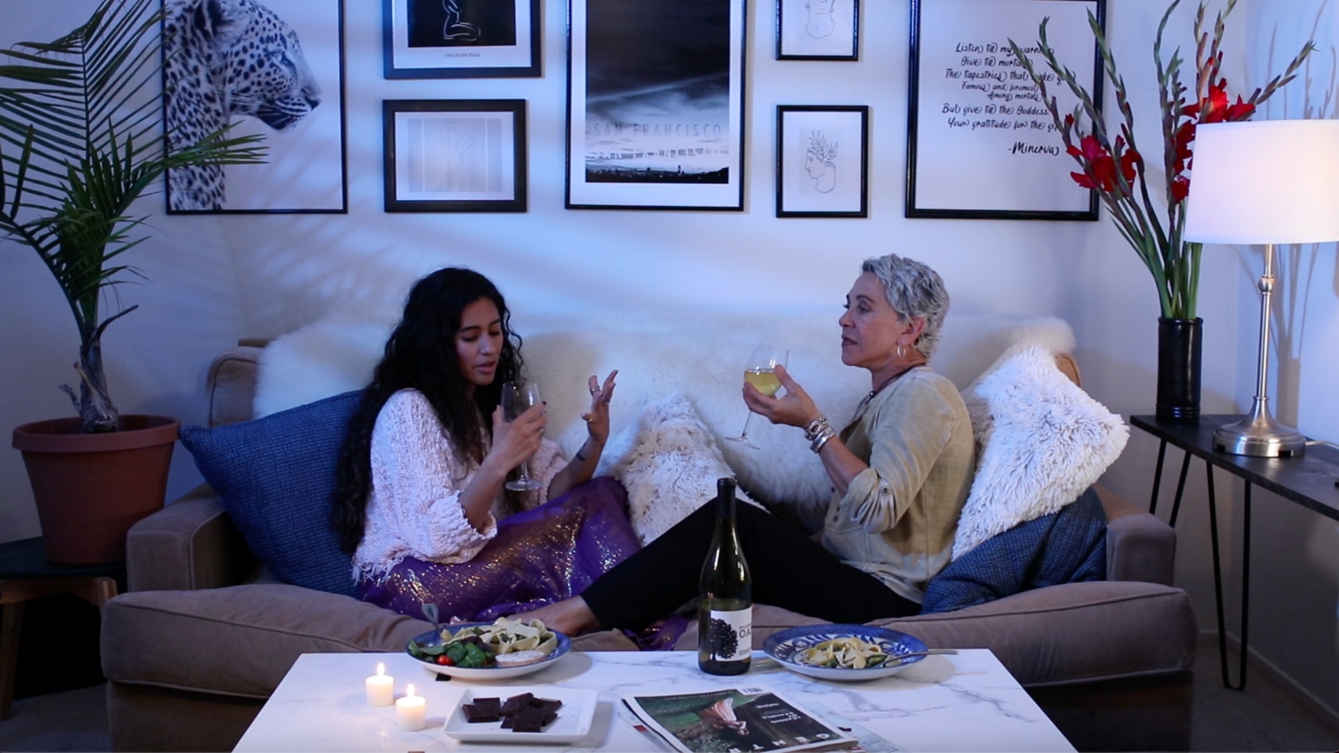 two women sitting on couch drinking wine